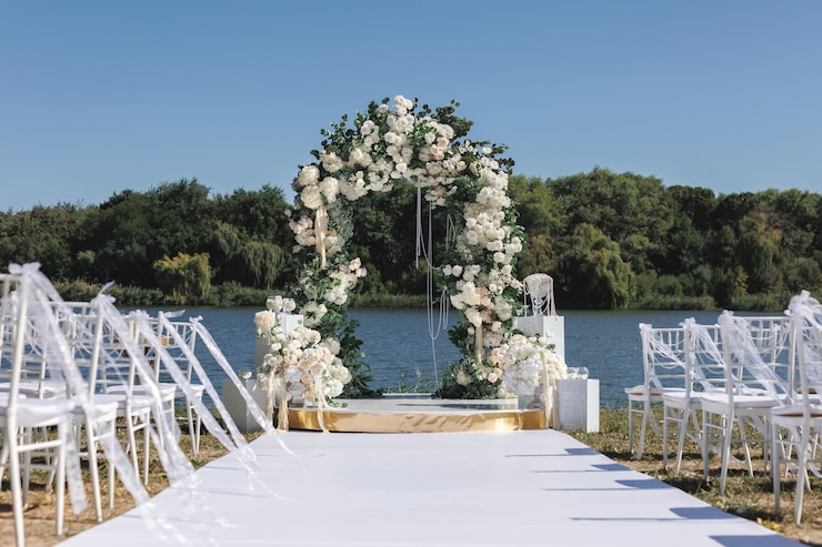 Foto uma cerimônia de casamento com cadeiras brancas um caminho e um arco de flores brancas na margem do lago