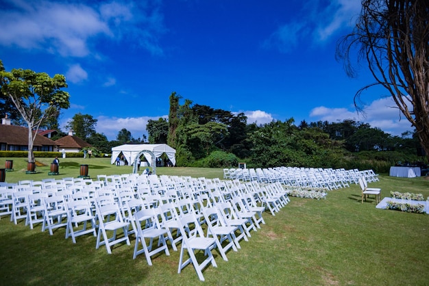 uma cerimônia de casamento com cadeiras na grama e um céu azul com nuvens