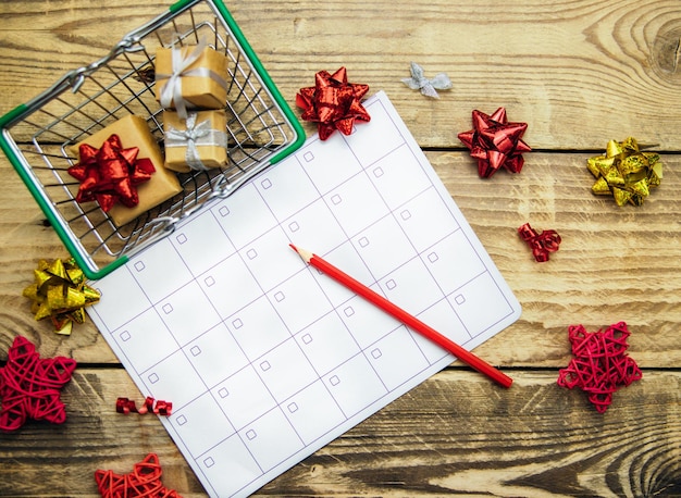 Uma cesta de compras com presentes, um calendário ou uma lista de tarefas. o conceito de planejar compras, estabelecer metas e realizar desejos para o próximo ano. compras online, black friday, venda.