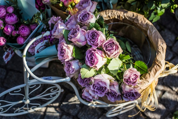 Uma cesta de rosas roxas na pequena bicicleta decorativa