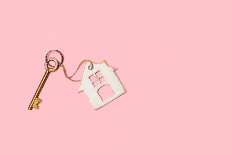 Foto uma chave antiga com um chaveiro em forma de casa em um fundo rosa com espaço de cópia
