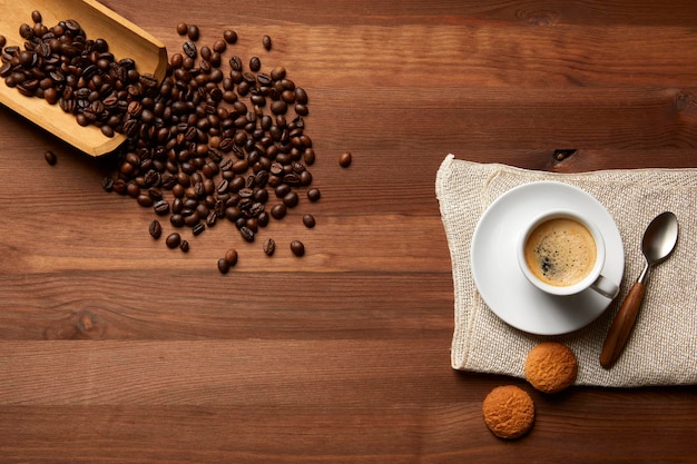 Uma chávena de café e grão de café visto de cima em uma mesa de madeira