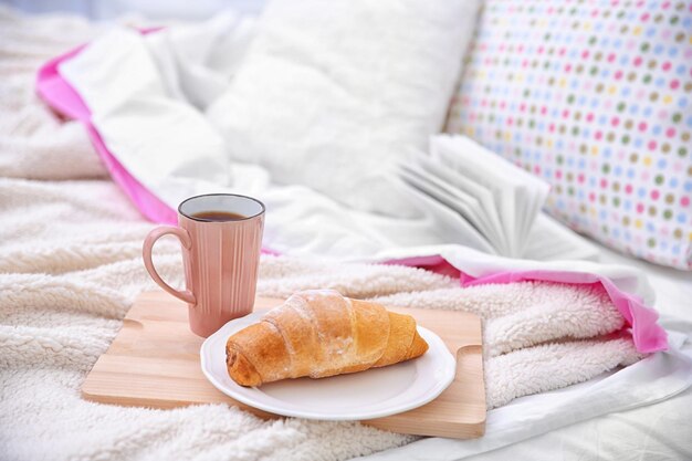 Uma chávena de café e um croissant saboroso na cama .