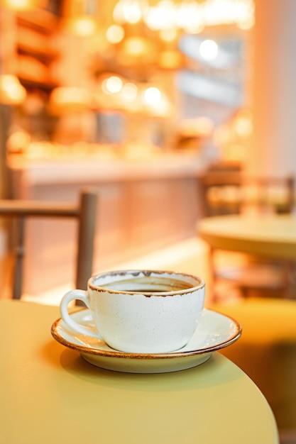 Uma chávena de café preto em um prato na borda da mesa em um espaço de cópia de café