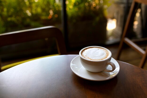 Foto uma chávena de cappuccino sentada em uma mesa ao lado de uma janela