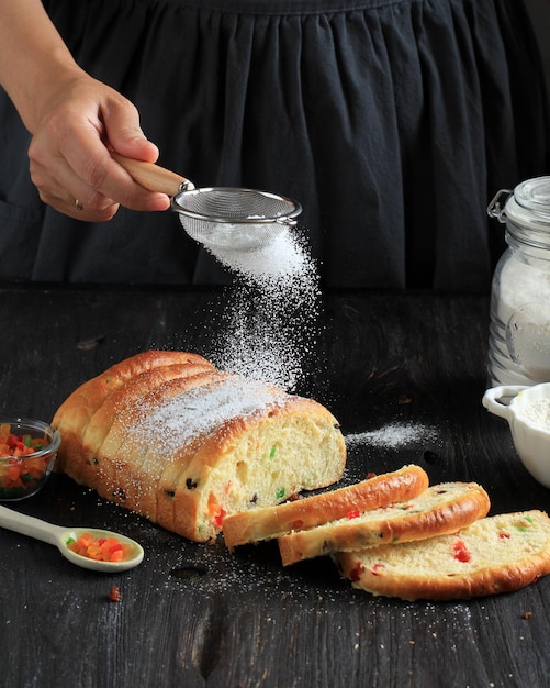 Uma chef feminina polvilha farinha de açúcar em um pão de Natal Stollen através de uma pequena peneira. Movimento Congelado