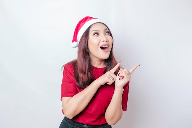 Uma chocada mulher de Papai Noel asiática está mostrando seu telefone isolado pelo conceito de Natal de fundo branco