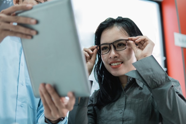 Uma cliente experimenta os óculos para olhar para a tela do tablet enquanto está no oculista