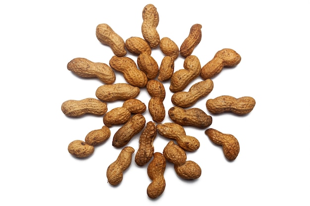 Uma coleção de nozes de amendoim não refinadas está na forma de um círculo ou sol em um fundo branco isolado com um traçado de recorte Padrão de amendoim cru