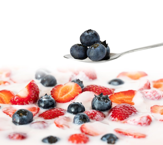 Foto uma colher de frutas e iogurte com uma colher de iogurte.