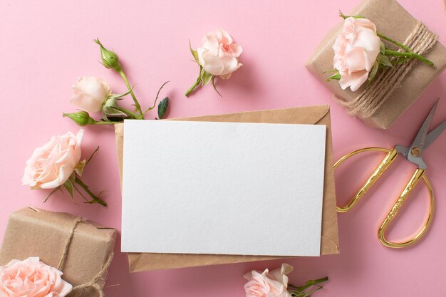 Uma composição de dia dos namorados de presentes embalados ecologicamente, um envelope kraft e flores frescas em um fundo rosa claro Banner vintage