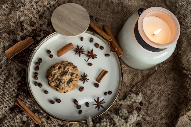 Uma composição elegante de velas, pratos com borda dourada, biscoitos e especiarias - anis, canela