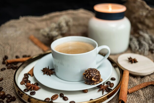 Uma composição estética de uma xícara de café preto com espuma e uma vela acesa