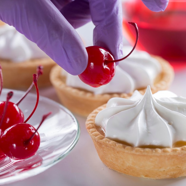 Uma confeiteira decora um bolo com uma cereja de coquetel produção de doces e bolos