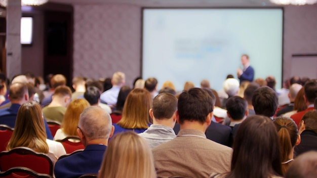 Uma conferência de negócios no salão pessoas sentadas nas cadeiras e assistindo a apresentação