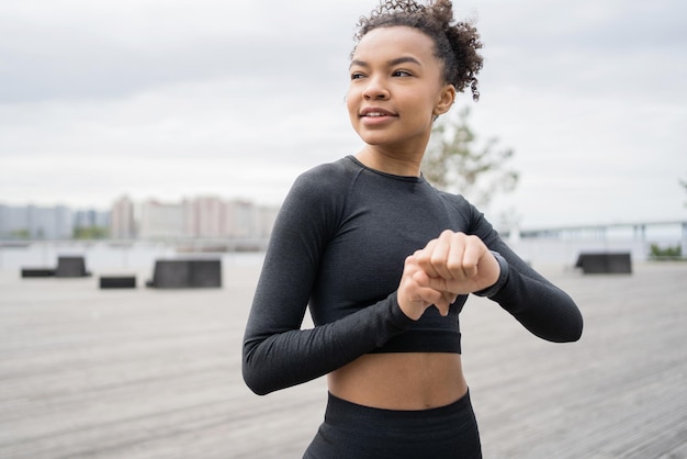 Uma corredora usa um relógio de fitness para treinar o treinador está vestido com um agasalho