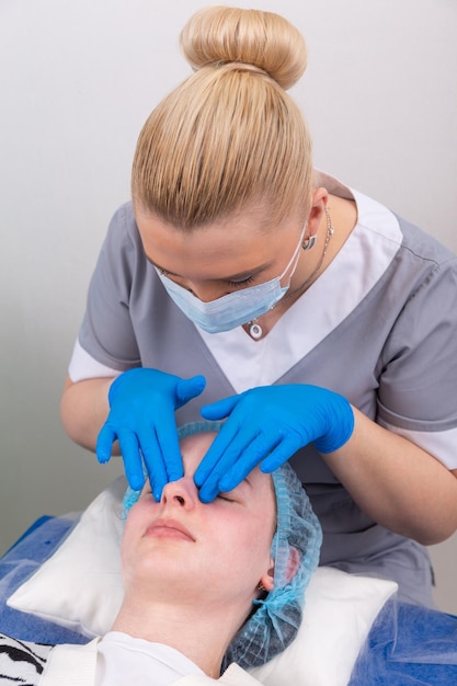 Uma cosmetologista feminina trata manualmente a pele do paciente com um gel hidratante e tonificante