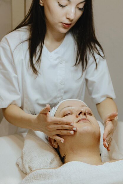 Uma cosmetologista massagem o queixo de uma paciente