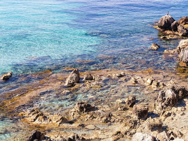 Uma costa rochosa com água limpa e um céu azul