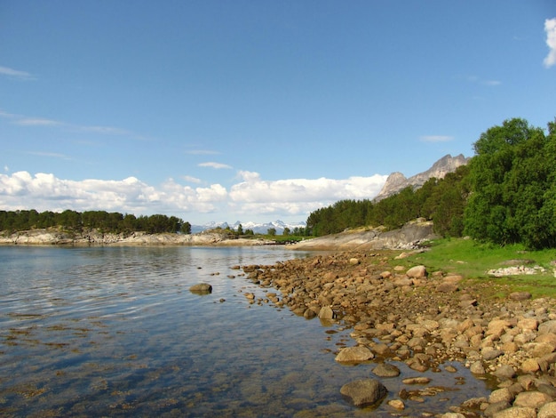 uma costa rochosa com um lago e montanhas ao fundo