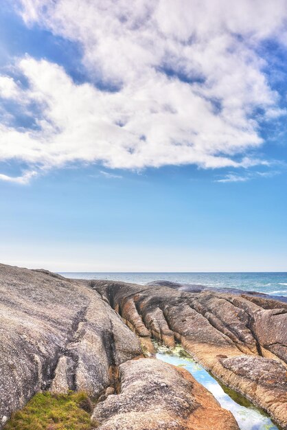 Uma costa rochosa e uma vista marinha do oceano com espaço de cópia de céu azul e uma montanha ao fundo em Camps Bay Cape Town África do Sul Calma serena tranquila praia e paisagem natural