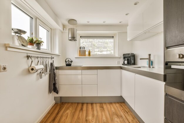 uma cozinha branca com aparelhos de aço inoxidável e uma janela