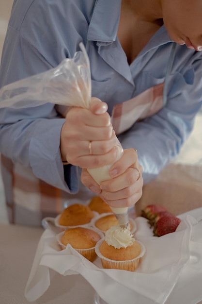 Uma cozinheira de pastelaria coloca cobertura em cupcakes mostrando seus produtos caseiros assados