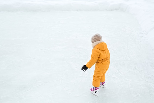 Uma criança aprende a patinar em um lago congelado.