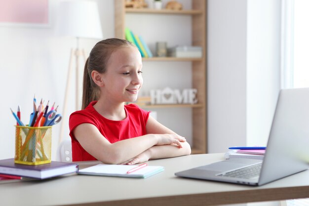 Uma criança aprende online em casa por meio de um laptop moderno na internet