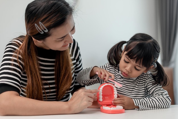 Uma criança asiática bonita brincando com um brinquedo médico dentista mostra como limpar e cuidar dos dentes Odontologia e medicina