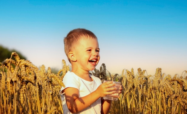 Uma criança bebe água no fundo do campo