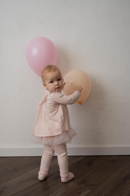 Uma criança bonita comemora seu aniversário com um bolo contra uma parede branca