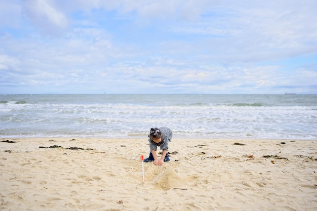 Uma criança brinca na areia da praia