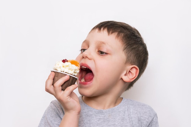 Uma criança caucasiana comendo um delicioso bolinho de chocolate doce com creme branco e frutas