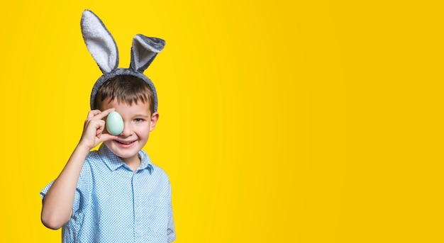 Uma criança com ovo de Páscoa em fundo amarelo