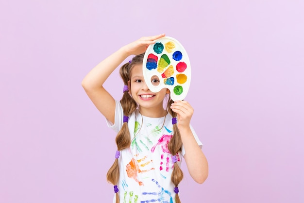 Uma criança com tintas em um fundo isolado uma garotinha em uma camiseta com impressões de mão com tintas uma paixão por pintar