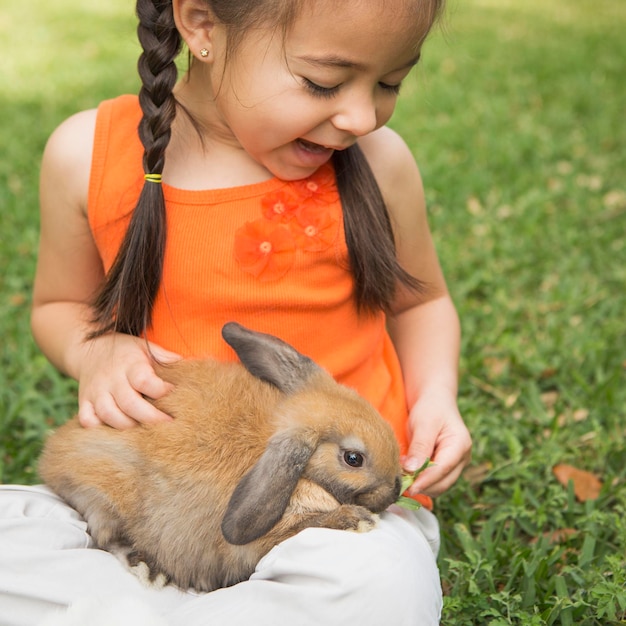 Foto uma criança com um coelho marrom no colo