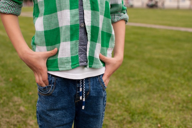Uma criança com uma camisa xadrez verde e jeans em um fundo de gramado