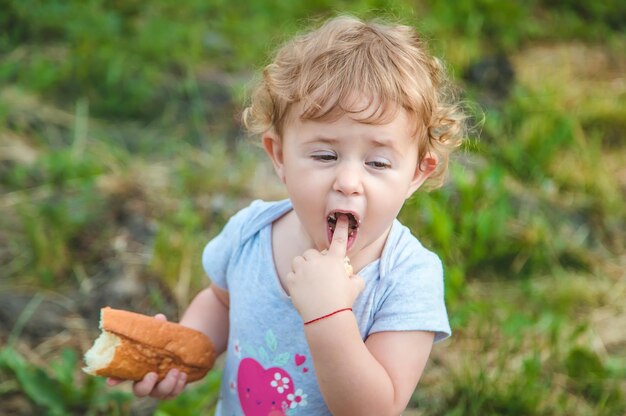 Uma criança come pão no parque Foco seletivo