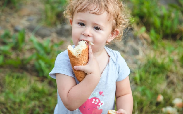 Uma criança come pão no parque Foco seletivo