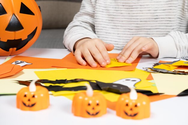 Uma criança cria uma abóbora sem papel Origami para a preparação do Halloween