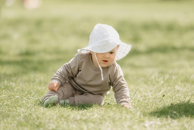 Uma criança de 7 meses com o chapéu panamá está brincando no prado