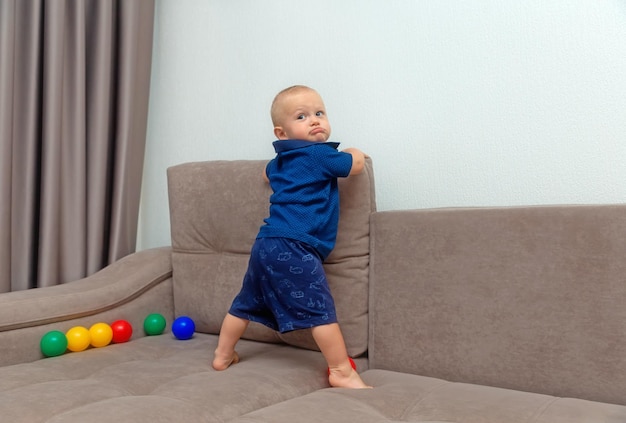 Uma criança de um ano, um menino aprende a andar na sala de estar