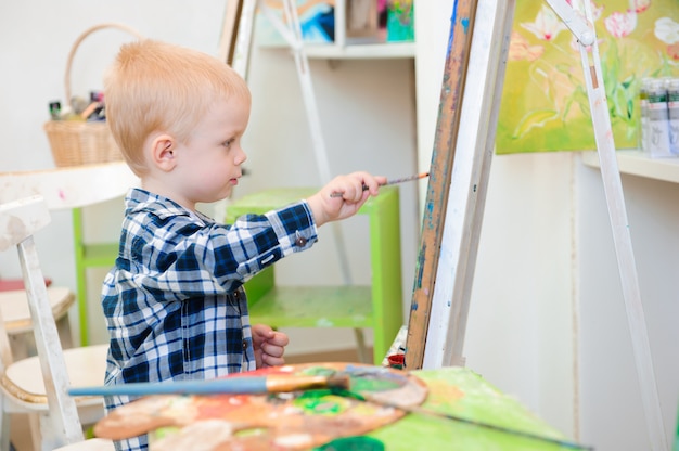 Uma criança desenha uma pintura na aula de arte