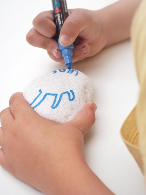 Uma criança desenhando um caranguejo em uma pedra branca