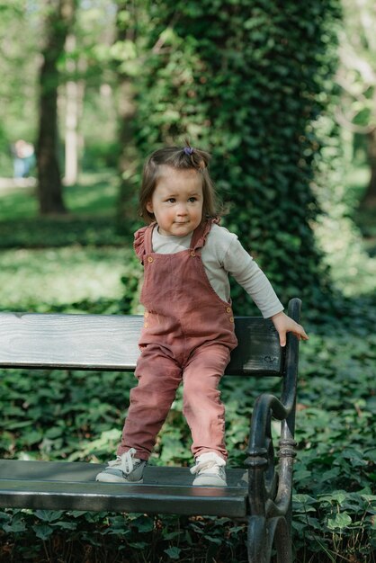 Foto uma criança do sexo feminino está no banco do jardim no parque