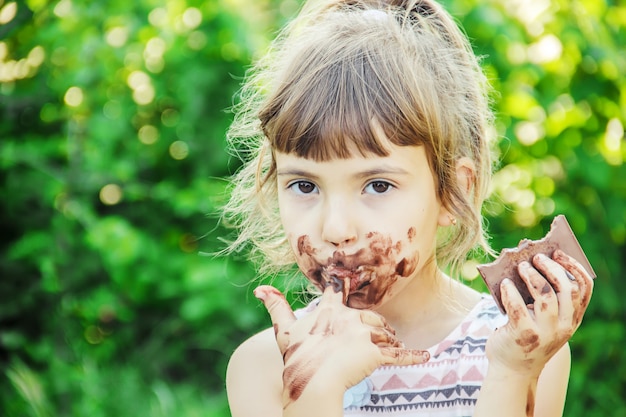 Uma criança doce come chocolate. Foco seletivo.