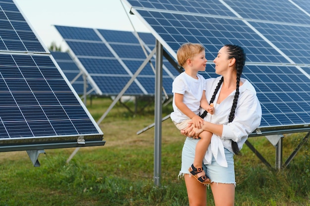 Uma criança e sua mãe ao ar livre ao lado de painéis solares em um dia ensolarado em uma fazenda