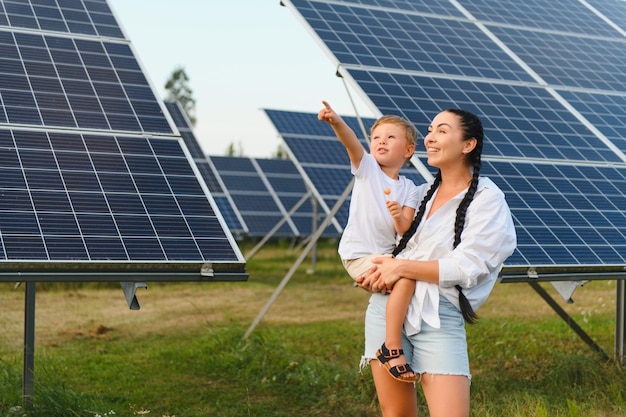 Uma criança e sua mãe ao ar livre ao lado de painéis solares em um dia ensolarado em uma fazenda