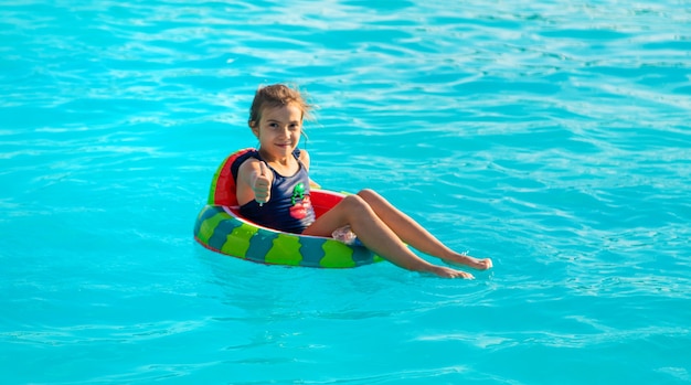 Uma criança em círculo nada na piscina. Foco seletivo. Miúdo.